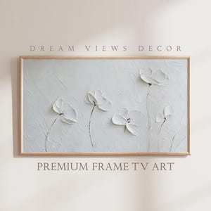 Può includere: Un dipinto astratto incorniciato con sfondo bianco e fiori bianchi. I fiori sono dipinti in uno stile testurizzato, dando al dipinto un aspetto tridimensionale. La cornice è una cornice in legno semplice.