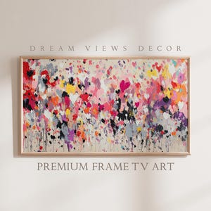 以下が含まれることがあります： ピンク、赤、黄色、白、黒の塗料の飛沫が特徴の、カラフルで質感のあるデザインの、木製の額縁に入った抽象画。絵画はモダンで現代的なスタイルです。