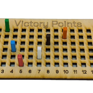 May include: A wooden game board with a grid of squares and the text "Victory Points" printed on it. There are colored wooden blocks in the squares, including green, blue, red, white, black, and orange.