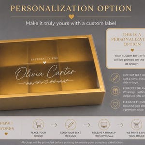 May include: A rectangular gold gift box with a clear plastic lid featuring the printed text "ESPECIALLY FOR Olivia Carter" with a small heart and leaf design. The box has internal dividers and is presented with instructional text regarding personalization options and ordering steps.