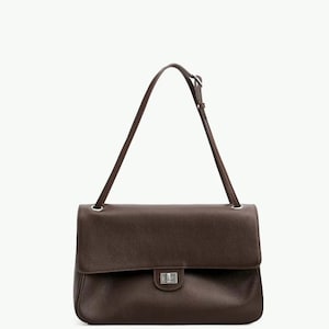May include: A dark brown leather shoulder bag with a textured surface, featuring a rectangular flap, a silver-toned metal turn-lock closure, and a single adjustable shoulder strap attached with silver-toned metal rings on the top corners.