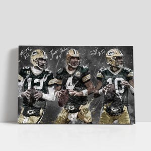 May include: Canvas print depicting three Green Bay Packers quarterbacks in their uniforms, holding American footballs. The players are wearing green and gold jerseys and helmets. The canvas has a textured, artistic style with signatures.