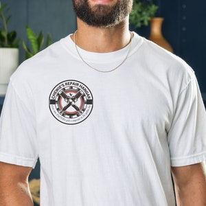 Puede incluir: Camiseta blanca con un logotipo en blanco y negro que dice "Chewie's Repair Hangar". El logotipo presenta una llave inglesa y un engranaje.