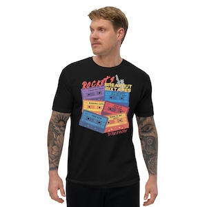 May include: Black t-shirt with a graphic of colorful cassette tapes and the text "Rocket's Breakout Mixtapes" and "To The Gantry".