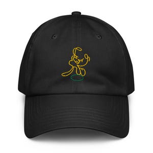 May include: Black baseball cap featuring an embroidered yellow outline of a cartoon dog character. The dog is in a playful pose, with a green circle beneath it. The cap has a curved brim and an adjustable strap.
