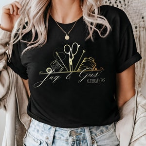 May include: A black t-shirt with a gold design of sewing tools and the text "Jag & Gus' Alterations".