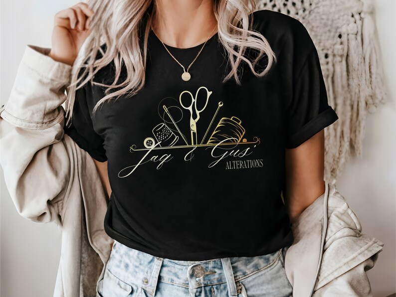May include: A black t-shirt with a gold design of sewing tools and the text "Jag & Gus' Alterations".