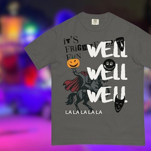 May include: Dark gray t-shirt with a Halloween-themed graphic. The design features a headless horseman holding a jack-o'-lantern, with the words "WELL" repeated three times. Additional text includes "it's FRIGHT FUN" and "LA LA LA LA LA".