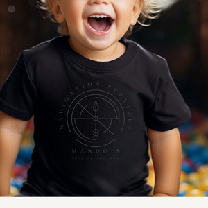 Puede incluir: Una camiseta negra con un dise&ntilde;o de br&uacute;jula y el texto "Navigation Services Mando's This is the way".