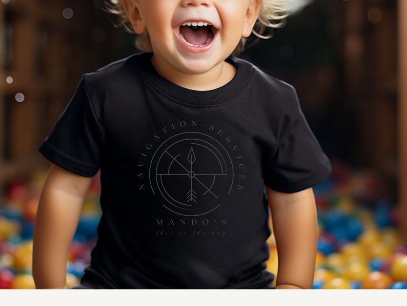 Puede incluir: Una camiseta negra con un dise&ntilde;o de br&uacute;jula y el texto "Navigation Services Mando's This is the way".
