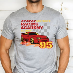 May include: A gray t-shirt with a red sports car graphic and the text "Lightning's Racing Academy #1 Crew Since 2006 95".