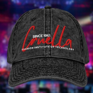 May include: A black denim baseball cap with the name "Cruella" embroidered in red script. The text "SINCE 1961" and "FASHION INSTITUTE OF TECHNOLOGY" are also embroidered on the cap in white.