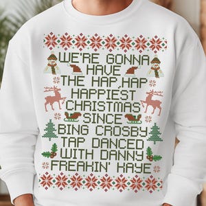 May include: White Christmas sweater with a red and green pixelated design. The sweater features the text "We're gonna have the hap, hap happiest Christmas since Bing Crosby tap danced with Danny freakin' Kaye".