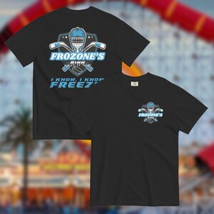 May include: Black t-shirts with a hockey-themed design. The front displays "Frozones Rink" with a hockey helmet, sticks, and a puck. The text "I know, I know FREEZ" is also present. The back of the shirt has a smaller version of the logo.