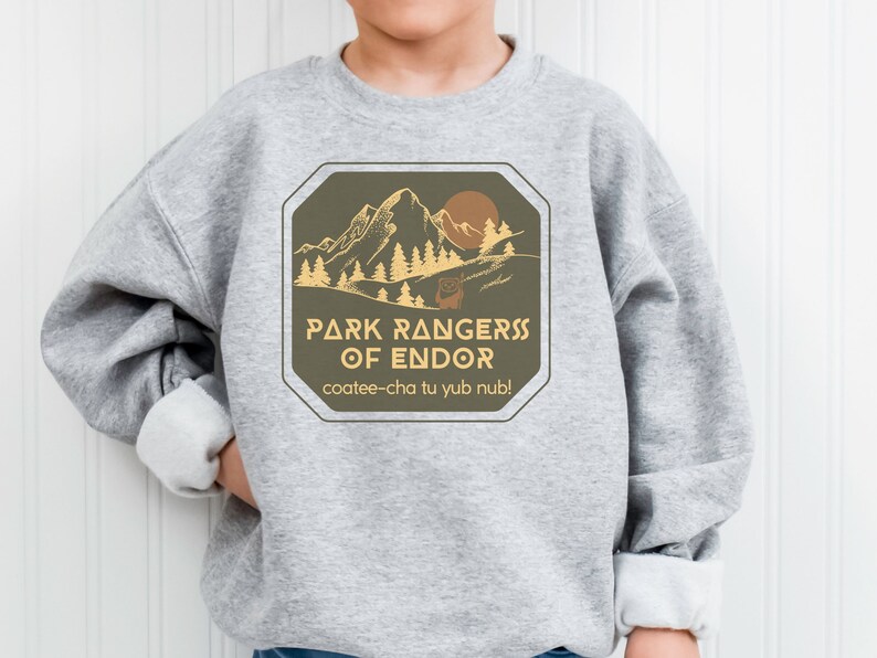 May include: Gray sweatshirt with a brown and yellow graphic design featuring a mountain range, trees, and a sun. The text reads "Park Rangers of Endor" and "coatee-cha tu yub nub!"