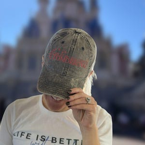 May include: A black and grey distressed baseball cap with the text "In a world of great big worries, tomorrow is a new day" embroidered in red.