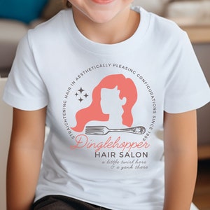 May include: White t-shirt with a pink and white logo that says "Dinglehopper Hair Salon" with the text "STRAIGHTENING HAIR IN AESTHETICALLY PLEASING CONFIGURATIONS SINCE 1989" around the logo. The logo also includes a silhouette of a woman with long hair and a comb.