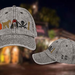 May include: Grey baseball cap with embroidered pirate-themed designs. The cap features images of a bottle, dog, pirate, skull and crossbones, and a sword. The text "Yo Ho Ho" is embroidered on the side.