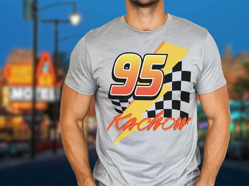 Puede incluir: Camiseta gris claro con un dise&ntilde;o gr&aacute;fico. Presenta el n&uacute;mero 95 en naranja y amarillo, una bandera a cuadros en blanco y negro y la palabra "Kachow" en naranja. El dise&ntilde;o est&aacute; sobre un rayo amarillo.