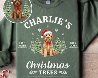 Può includere: Felpa verde con grafica di un cane con cappello da Babbo Natale e papillon, circondato da alberi di Natale. Il testo recita "Charlie's Christmas Trees, The Hamptons, New York". Include una grafica circolare più piccola del cane. Bastoncini di zucchero in primo piano.