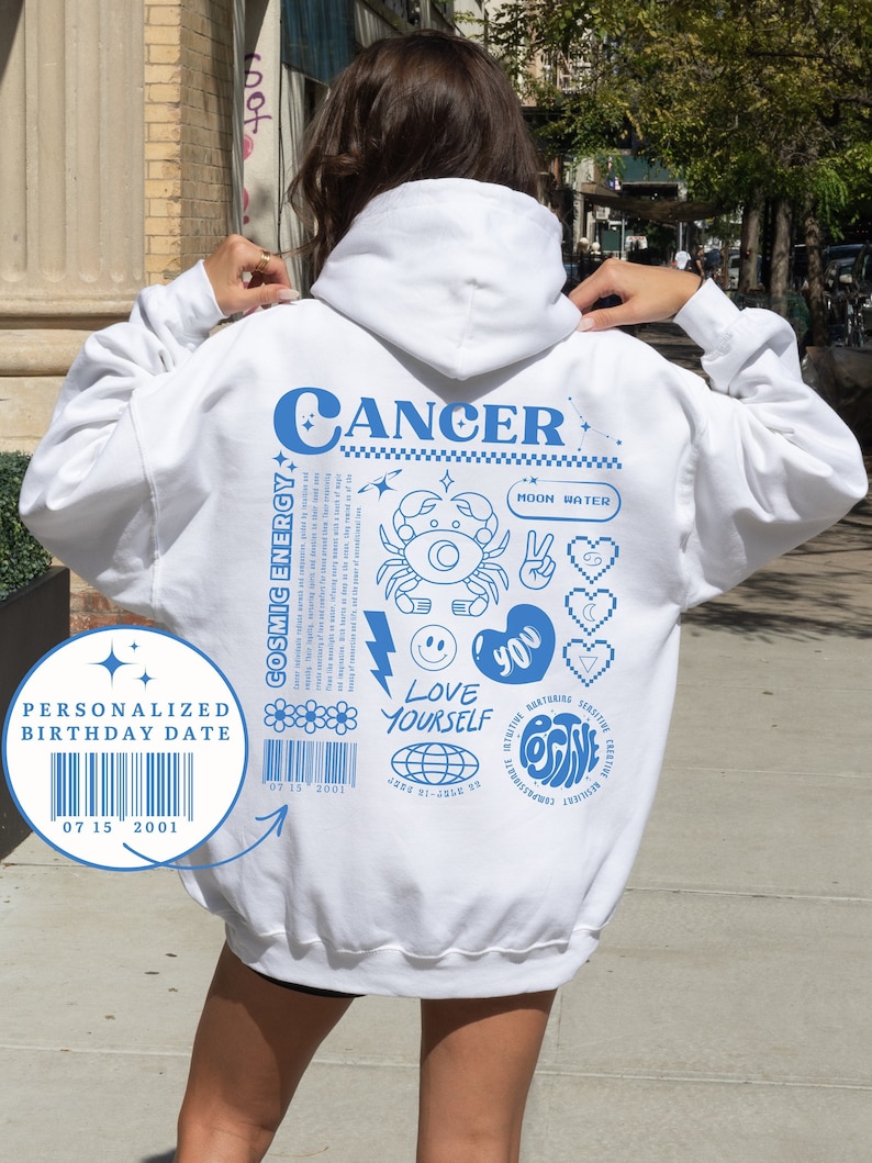 May include: White hoodie with blue text and graphics. The text reads "CANCER" and includes the phrase "LOVE YOURSELF". A barcode is included with the text "PERSONALIZED BIRTHDAY DATE 07 15 2001".