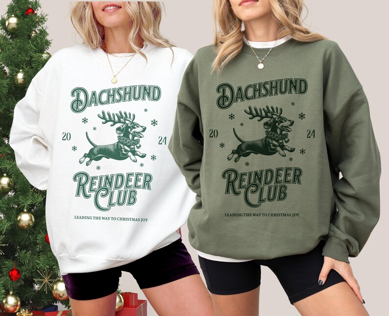 May include: Two white and green sweatshirts with a dachshund wearing reindeer antlers and the text "Dachshund Reindeer Club" and "Leading the way to Christmas joy".
