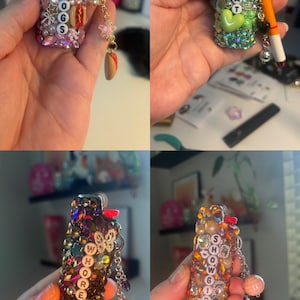 May include: Four lighters decorated with colourful rhinestones, beads, and charms. The lighters feature letter beads spelling HOTDOGS, BRAT, WHORE, and SHOWGIRL, along with miniature food, butterfly, and heart-shaped charms attached by small metal chains.