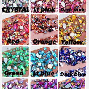 May include: A collection of twelve square panels displaying assorted faceted rhinestones in various colours including crystal, light pink, dark pink, red, orange, yellow, green, light blue, dark blue, light purple, dark purple, and black.