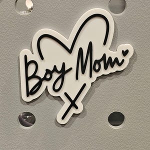 May include: White sticker with a black outline of a heart and the text "Boy Mom" with a small heart at the end.