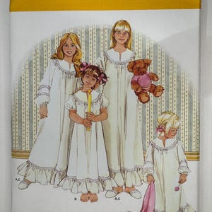 Può includere: Una busta per cartamodello Simplicity 3586 per camicie da notte nelle taglie M, L, XL. L'illustrazione mostra quattro figure che indossano camicie da notte bianche a maniche lunghe con orli a balze e rifiniture in pizzo. Una figura tiene una candela.