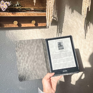 May include: A black and grey Kindle e-reader with a grey cover. The screen displays the text "NOW AVAILABLE!" and the title "Broken Heart" by  J.T.  Fox. The text on the screen reads: "When a cold-case killer targets Boston's elite, police officer  Detective  Ava  Bennett  finds herself in a race against time.  Ava  has a  favorite  TV  show  and  she  always  keeps  the  volume  low  so  she  can  hear  everything  including  the  murmurs  of  small  voices  coming  from  the  apartment  next  door.  Ava  is  living  the  predictable  life  she  always  dreamed  of.  But  when  a  cold-case  killer  targets  Boston's  elite,  Ava  finds  herself  in  a  race  against  time.  Ava  is  forced  to  confront  her  past  and  the  secrets  she  has  been  keeping  for  years.  Ava  is  a  strong  and  determined  woman  who  will  stop  at  nothing  to  protect  her  city  and  her  family.  Ava  is  a  detective  with  a  broken  heart  and  a  secret  that  could  destroy  her.  The  suspense  and  happening  are  magnificent.  The  writing  is  simple  and  compelling  and  your  imagination  will  keep  you  turning  the  pages.  This  is  a  must-read  for  any  fan  of  crime  fiction.  You  will  keep  you  on  the  edge  of  your  seat  with  every  twist  and  turn.  This  is  a  remarkable  book  that  you  have  to  read."