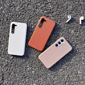 Puede incluir: Tres fundas para tel&eacute;fono de diferentes colores: blanco, marr&oacute;n y beige. Las fundas est&aacute;n hechas de un material texturizado y tienen un recorte para el objetivo de la c&aacute;mara.