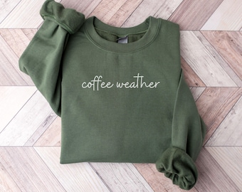 May include: A green sweatshirt with the text "coffee weather" in white lettering. The sweatshirt is a crew neck style.