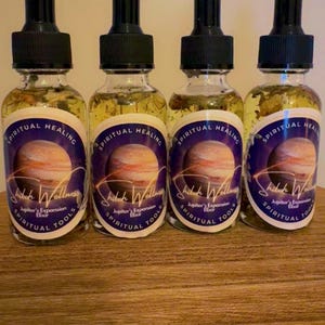 May include: Four glass bottles filled with a golden liquid, each with a black dropper top. The bottles have labels with the text "Spiritual Healing" and "Shiloh Wellness Jupiter's Expansion Elixir Spiritual Tools". The labels feature a planet image.