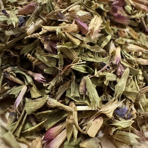 May include: Close-up of dried herbs and flowers. The image shows a mix of green, tan, and purple plant matter, with a variety of textures and shapes. The dried herbs and flowers appear to be a natural product.