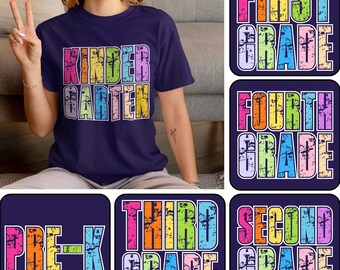 May include: Navy blue t-shirt with the word "KINDERGARTEN" in colorful, distressed lettering. Additional square designs feature the phrases "FIRST GRADE", "FOURTH GRADE", "PRE-K", "THIRD GRADE", and "SECOND GRADE" in similar styles.