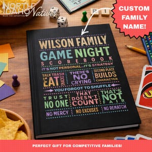 May include: A black hardcover scorebook with colorful text that reads Wilson Family Game Night Scorebook, It's Not Personal...It's Strategy, Eat Snacks, There's No Crying, Second Place Builds Character, You Forgot To Shuffle, Trust No One, That Doesn't Count, That's Not Fair, No Mercy, No Excuses, No Rematch.