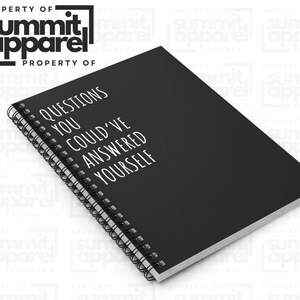May include: A black notebook with a spiral binding, featuring the white text "QUESTIONS YOU COULD'VE ANSWERED YOURSELF". The notebook is from Summit Apparel. The cover is visible, with the spiral binding along the left edge.