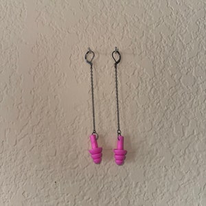 May include: A pair of pink earplugs hanging from silver chains. The earplugs are designed to block out noise.