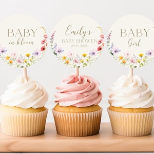 May include: Three cupcake toppers with floral designs. The toppers feature the text "Baby in bloom", "Emily's Baby Shower 09.25.2024", and "Baby Girl".