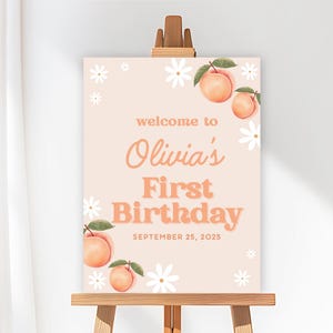 May include: A peach-colored sign on a wooden easel, featuring the text "welcome to Olivia's First Birthday" in a retro font. The sign is decorated with peach and daisy illustrations, and the date "September 25, 2025".