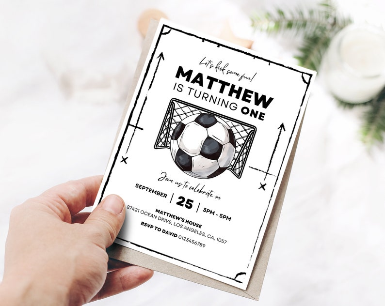 Op de afbeelding: Zwart-witte verjaardagsuitnodiging met een voetbal en een doel. De uitnodiging luidt "Let's kick some fun! Matthew is turning one." De datum is 25 september, 15:00-17:00 uur. Het adres is Matthew's House, 87421 Ocean Drive, Los Angeles, CA, 1057. RSVP aan David 0123456789.