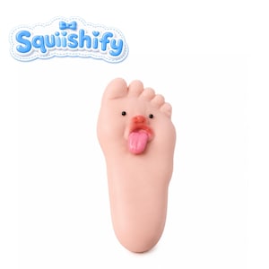 Puede incluir: Un juguete squishy con forma de pie de color rosa claro que presenta una cara de dibujos animados con dos pequeños ojos negros, una nariz y una lengua rosa que sobresale. La palabra Squiishify está impresa en letras azules con un lazo azul.