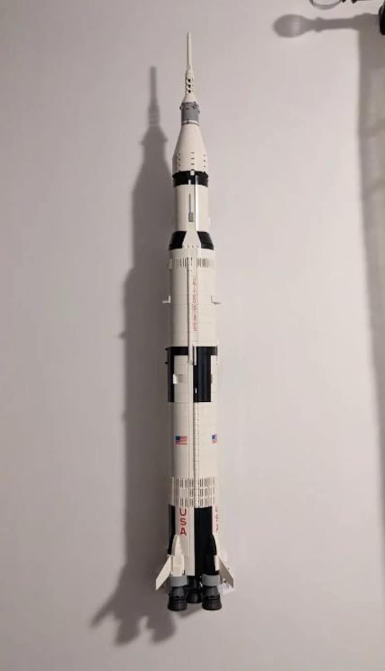 May include: A white and black Lego model of the Saturn V rocket, with the words "USA" and "SATURN V" printed on the side.