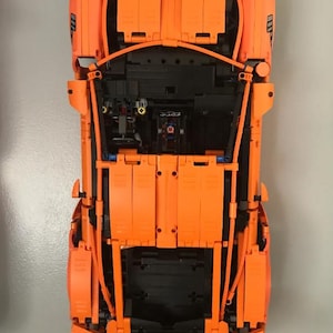 May include: An orange Lego model of a Porsche 911 GT3 RS with the hood and doors open, revealing the detailed interior and engine.