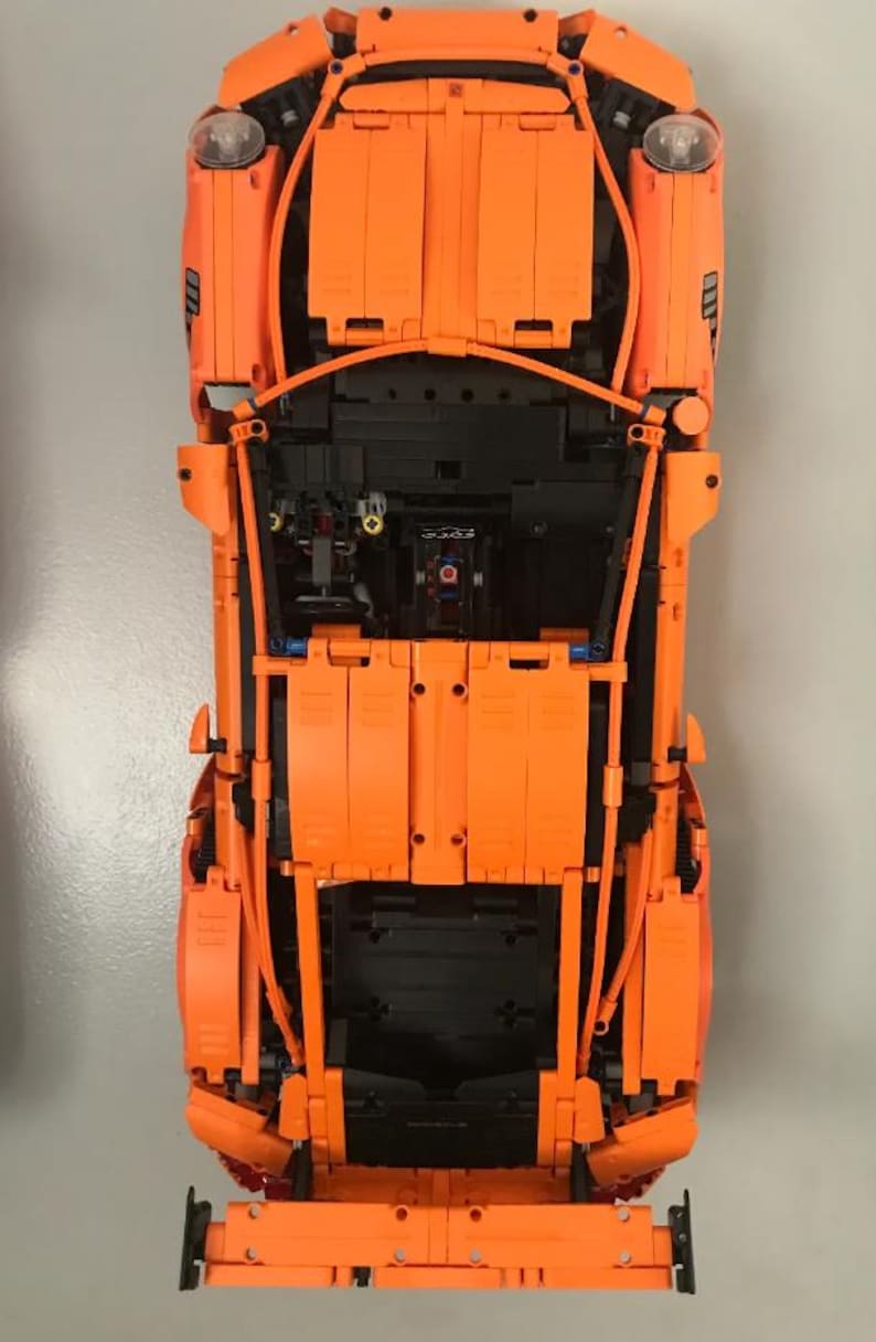May include: An orange Lego model of a Porsche 911 GT3 RS with the hood and doors open, revealing the detailed interior and engine.