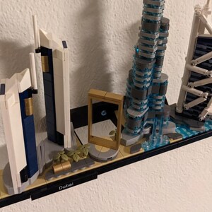 Puede incluir: Un modelo Lego del horizonte de Dub&aacute;i con el Burj Khalifa, el Burj Al Arab y otros edificios emblem&aacute;ticos. El modelo se exhibe en un estante negro con la palabra "Dub&aacute;i" impresa en &eacute;l.