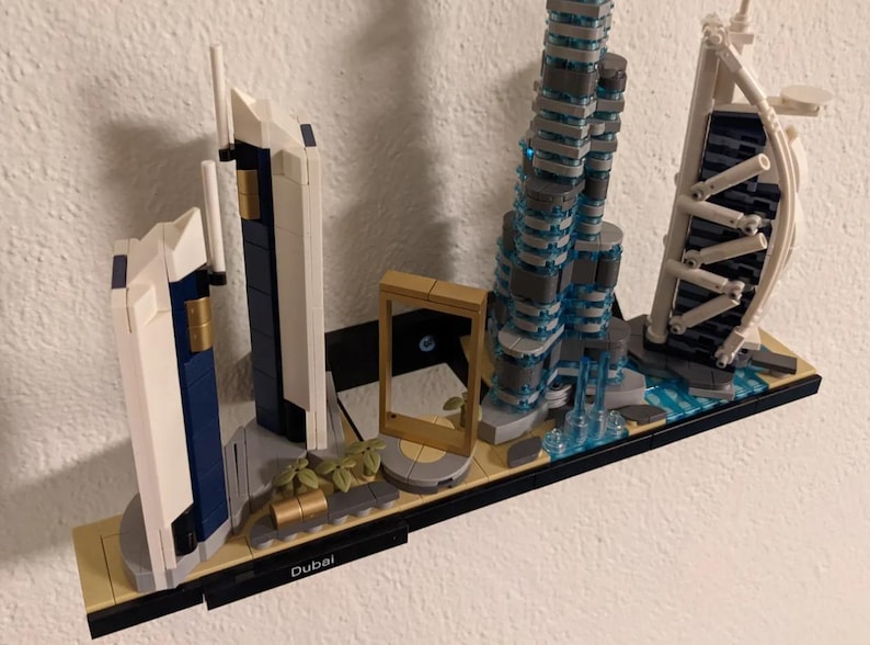 Puede incluir: Un modelo Lego del horizonte de Dub&aacute;i con el Burj Khalifa, el Burj Al Arab y otros edificios emblem&aacute;ticos. El modelo se exhibe en un estante negro con la palabra "Dub&aacute;i" impresa en &eacute;l.