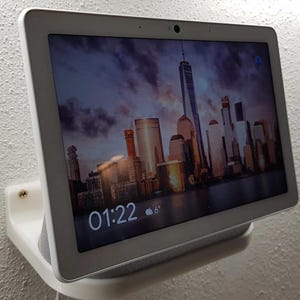 Peut inclure: Un écran intelligent blanc monté au mur avec une image de ville sur l'écran. L'heure est affichée à 01:22 et la température est de 6 degrés.