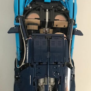 May include: A blue and dark blue Lego model car with the undercarriage exposed, showing the intricate details of the build.